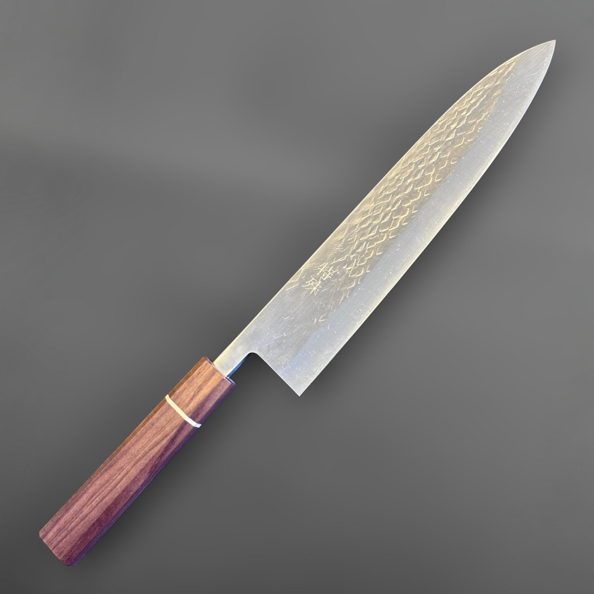 Tokushu Knife Tsuchime SLD Gyuto 240 mm, angled front view highlighting the long gyuto profile, pointed tip, and wood wa handle.