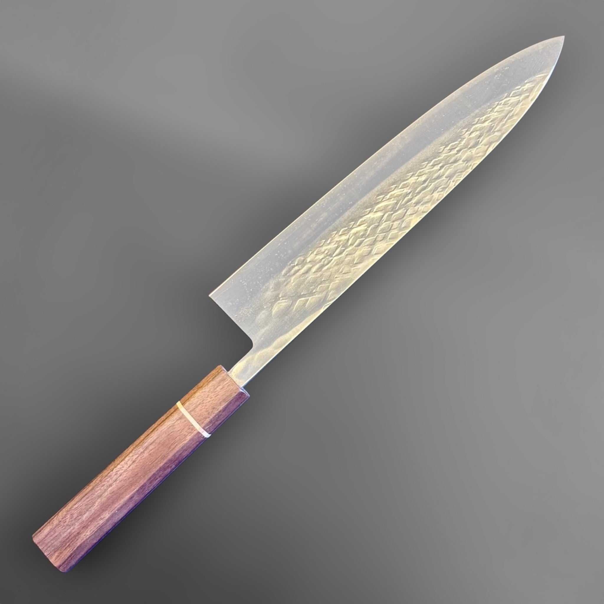 Tokushu Knife Tsuchime SLD Gyuto 240 mm, angled reverse-side view showing the hammered tsuchime finish and clean edge line.