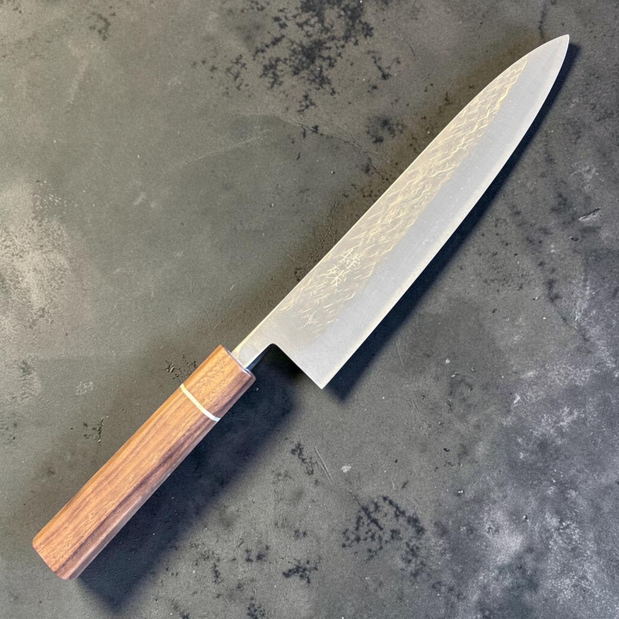Tokushu Knife Tsuchime SLD Gyuto 210 mm, angled reverse-side view with octagonal wood wa handle and subtle hammered blade texture.