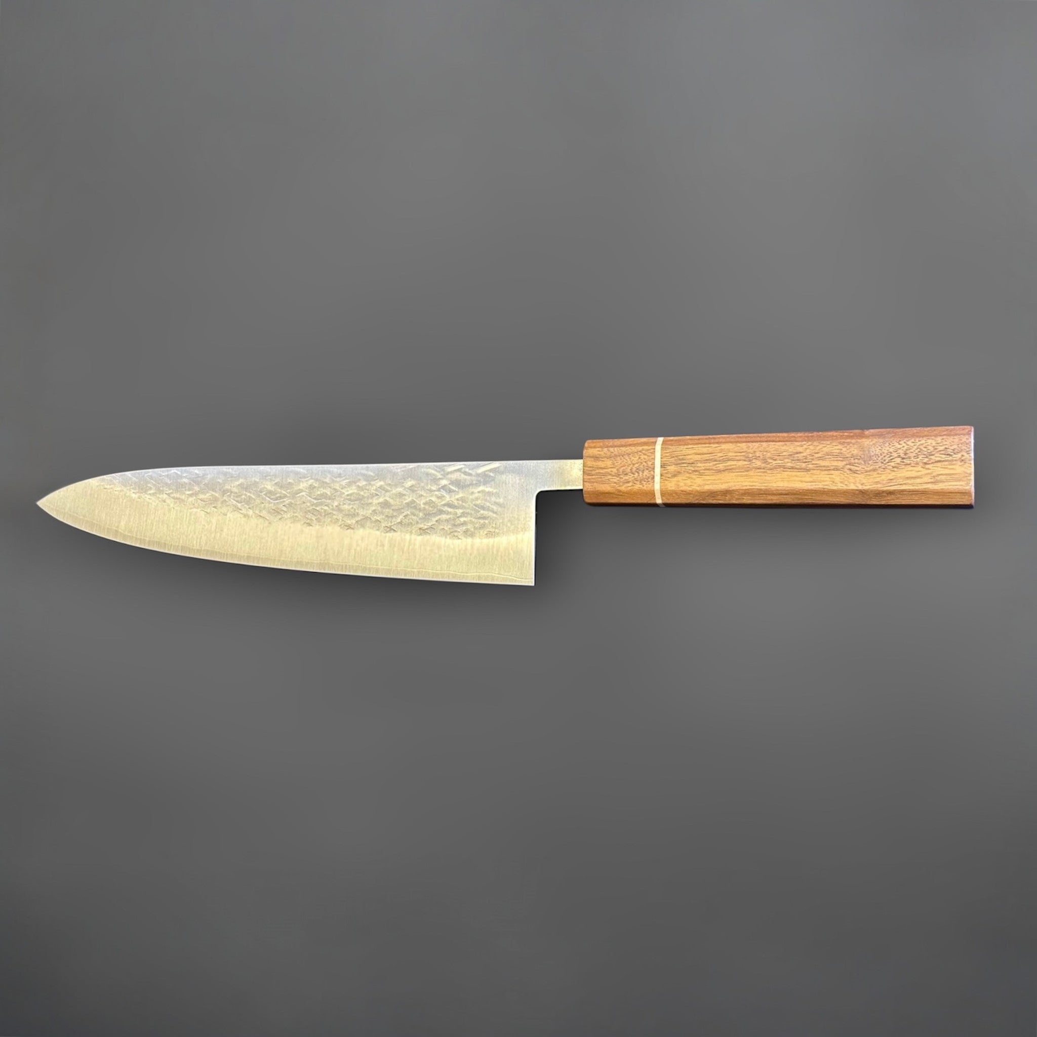 Tokushu Knife Tsuchime SLD Gyuto 210 mm, reverse full profile view showing the clean edge line, hammered cladding, and wooden wa handle.