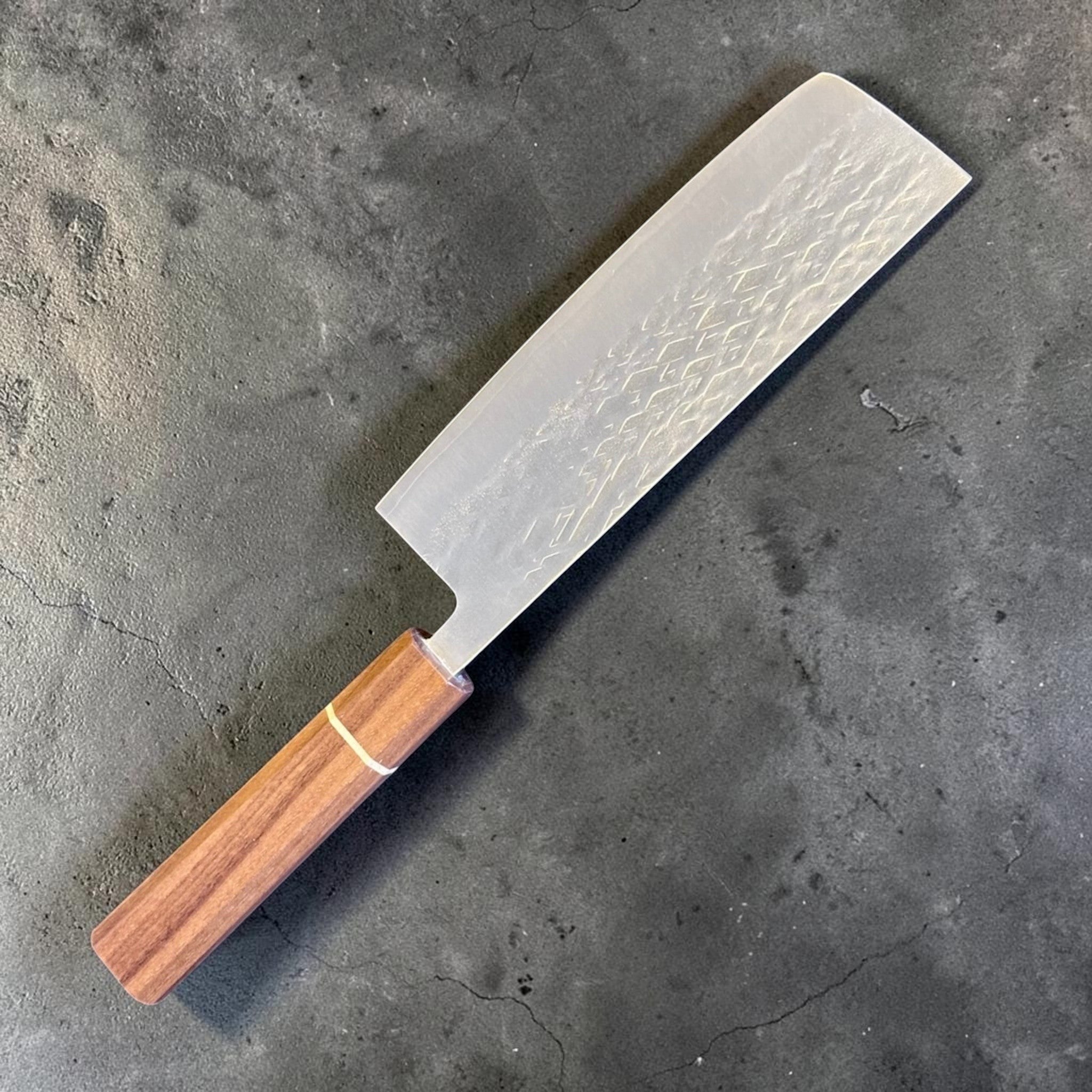 Tokushu Knife Tsuchime SLD Nakiri, angled reverse-side view with engraved kanji, tsuchime texture, and clean edge line.