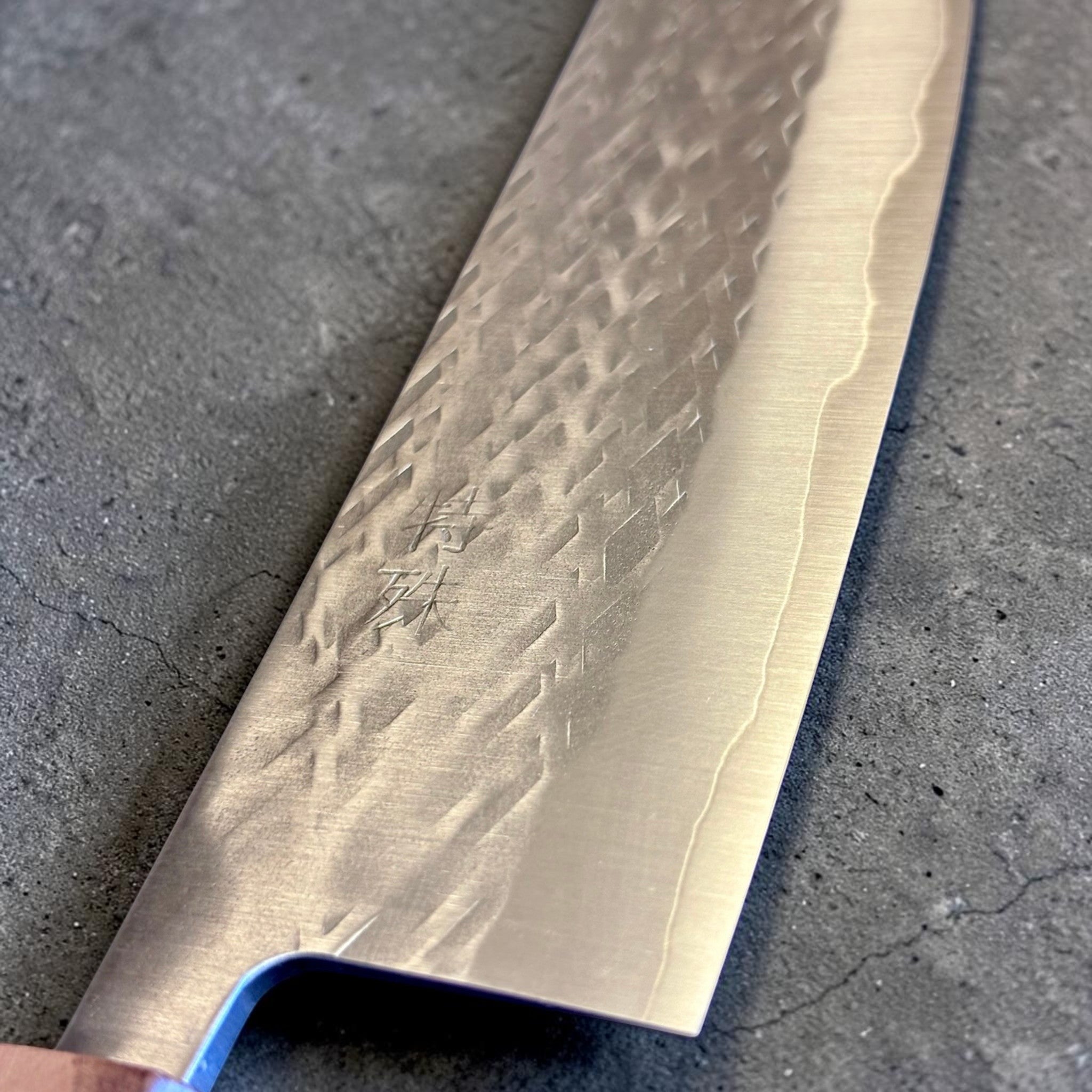 Tokushu Knife Tsuchime SLD Nakiri, close-up of the blade face with engraved kanji, tsuchime pattern, and cladding line.