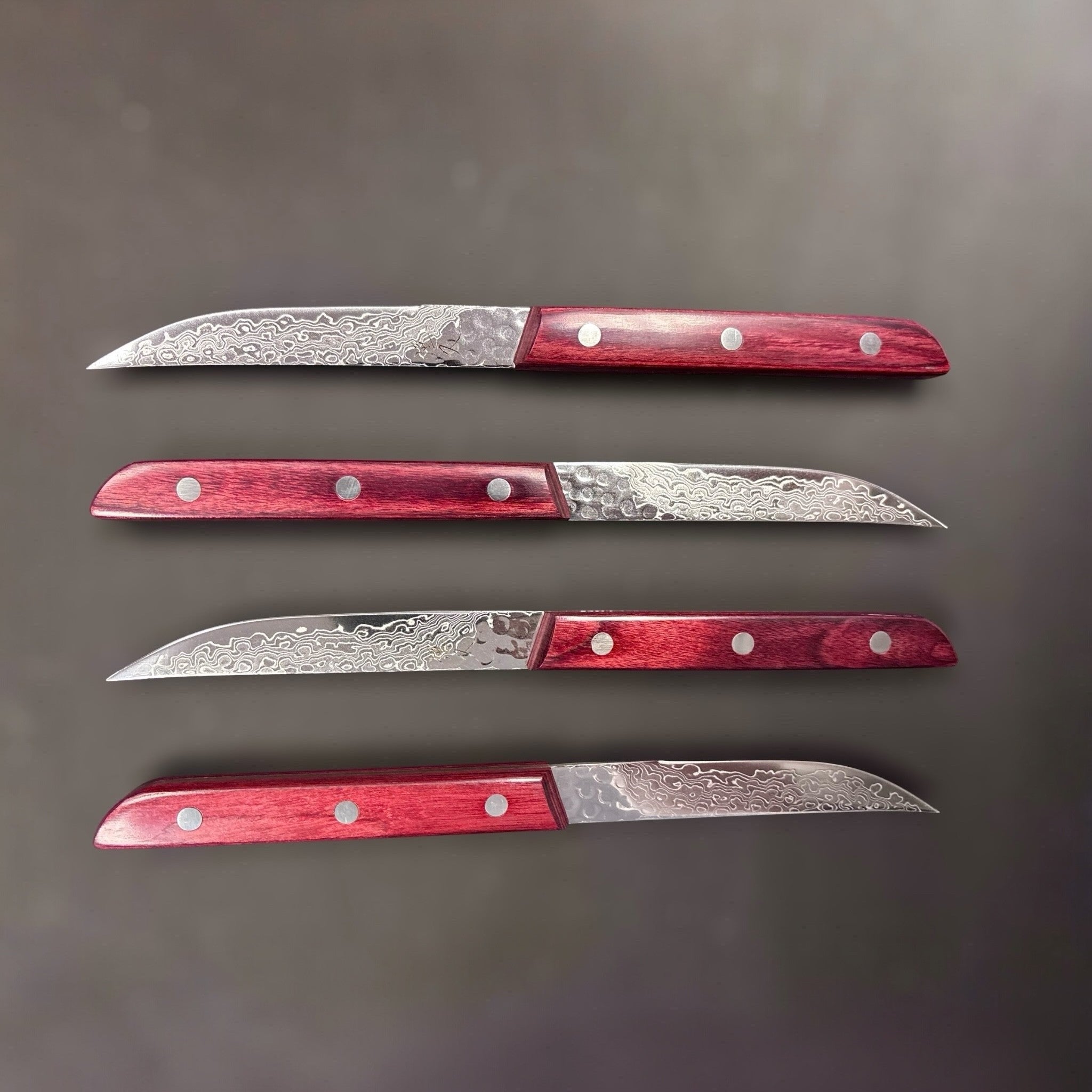 Tsunehisa AUS-10 Damascus Steak Knife, crimson pakka wood handle, 83 mm blade, visible layered Damascus pattern and light tsuchime texture.
