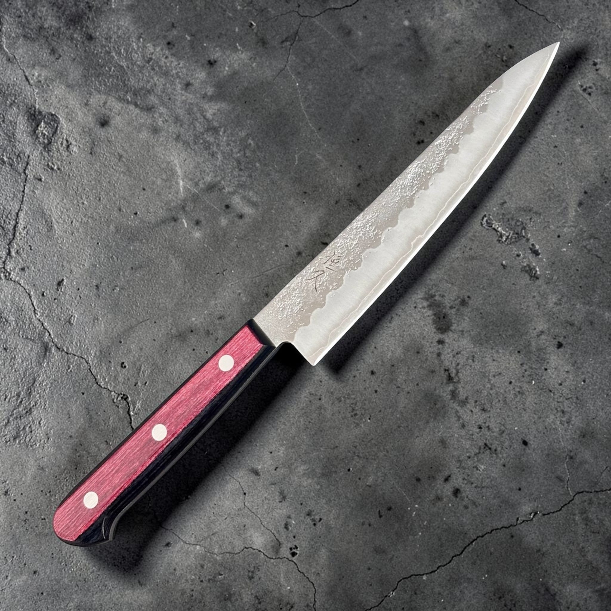 Tsunehisa Ginsan #3 Nashiji Petty 135 mm with red pakkawood scales, diagonal product view highlighting the pointed petty profile and textured blade face.
