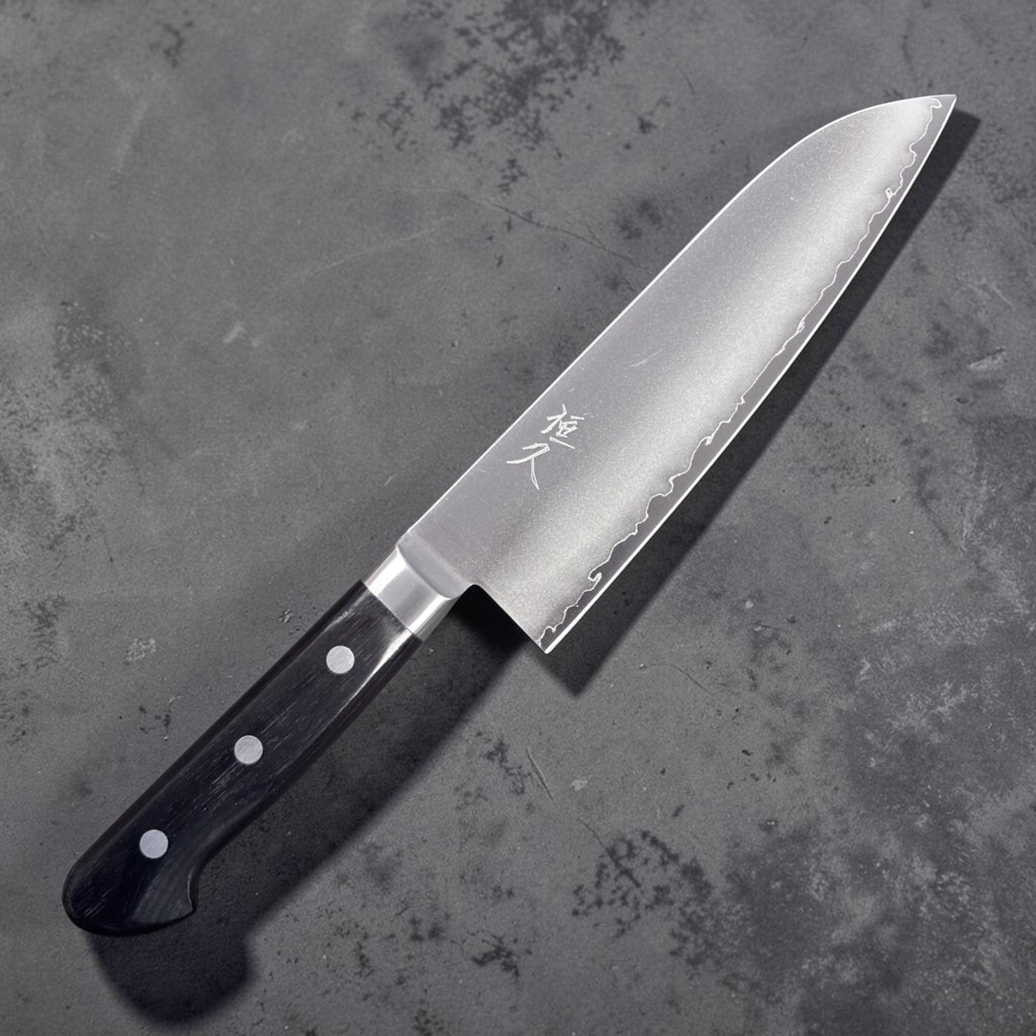 Tsunehisa VG-1 stainless steel Santoku 165 mm with black Western handle, right side blade face showing engraved kanji and brushed finish.