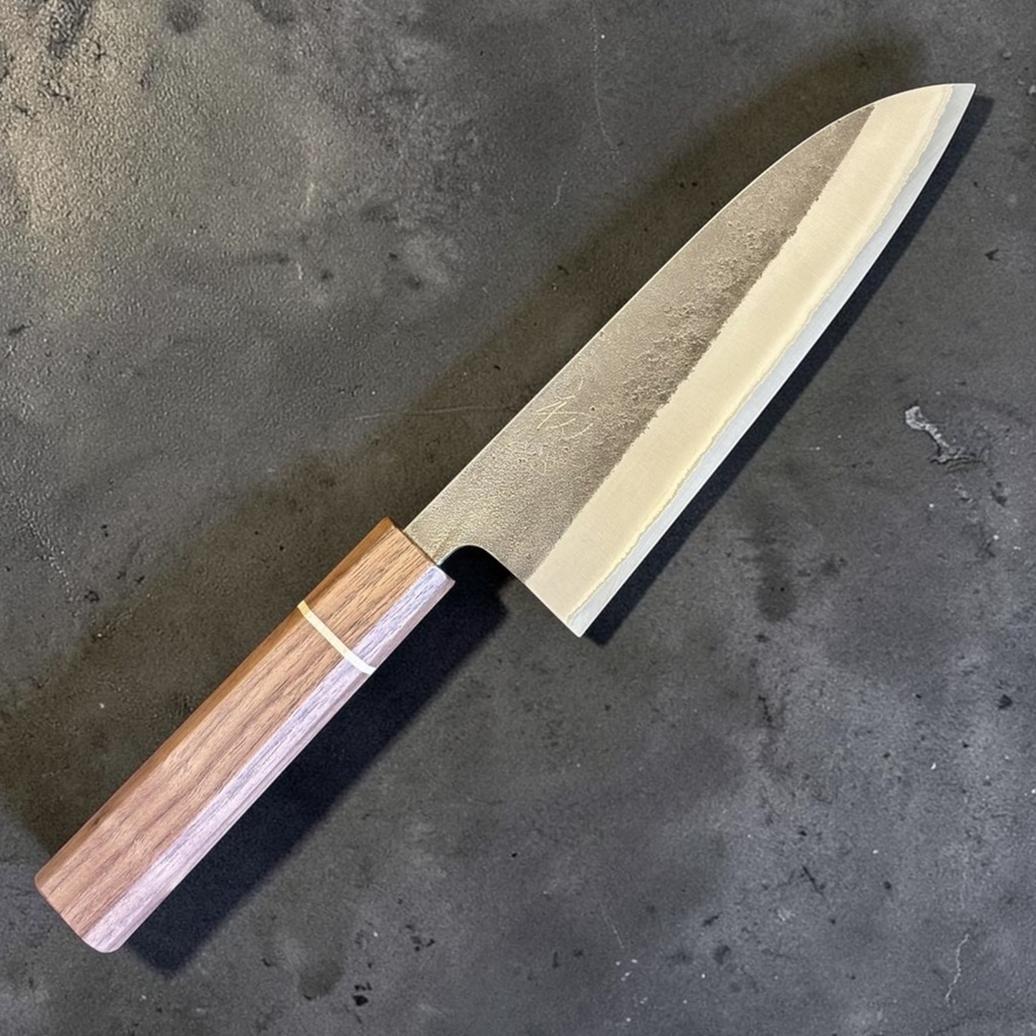 Yoshikane Nashiji Kurouchi Santoku with Sanjo walnut handle, diagonal product photo highlighting the blade profile and rustic finish.