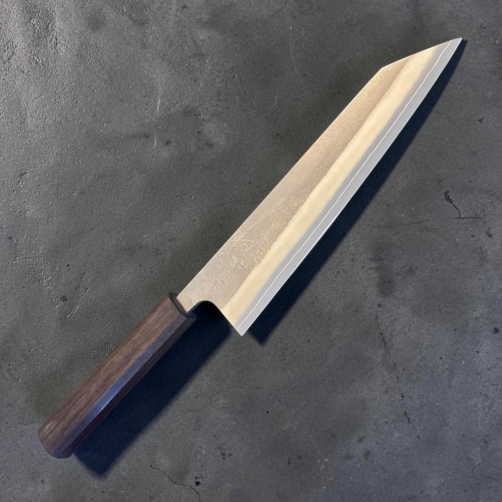 Yoshikane SKD Nashiji Kiritsuke 210mm with mono bubinga handle, angled maker-side view.