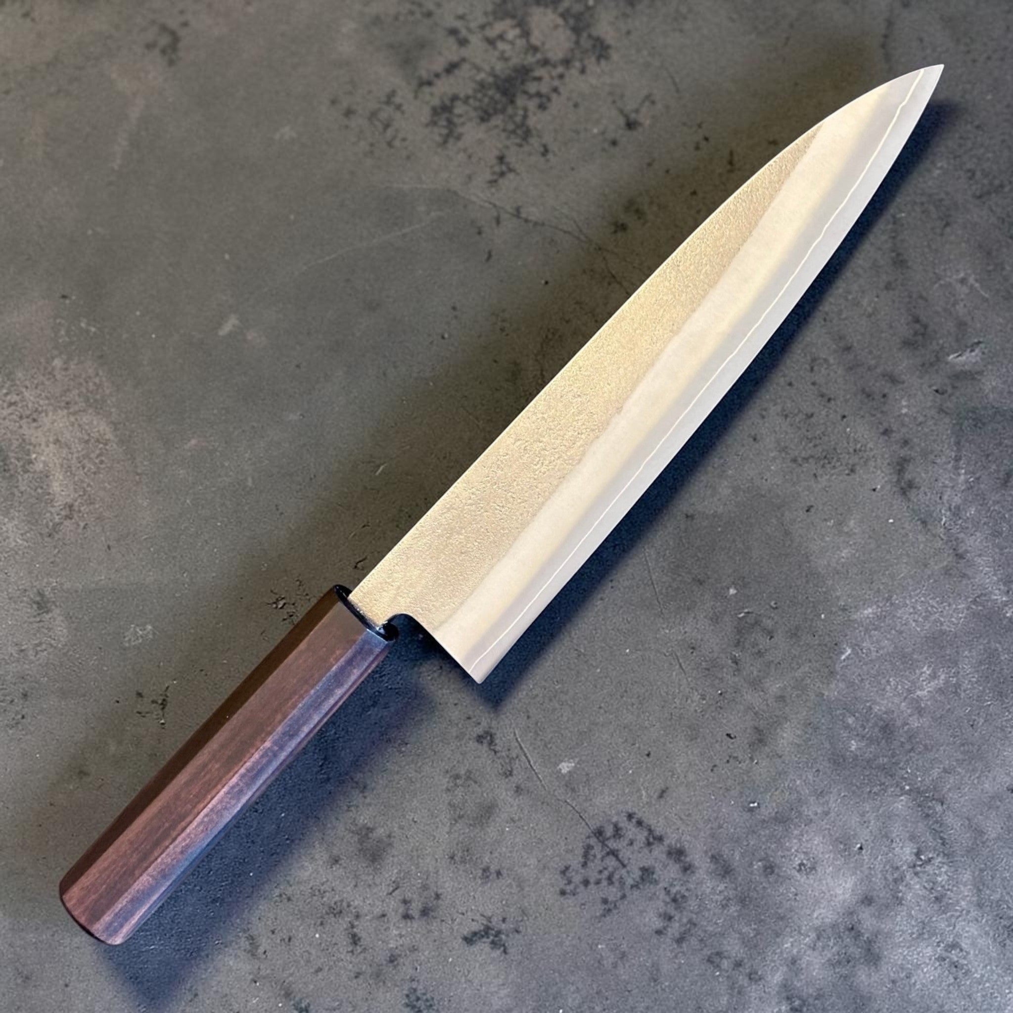 Yoshikane SKD Nashiji Gyuto 210 mm with mono ebony handle, angled front-side view showing nashiji blade finish.