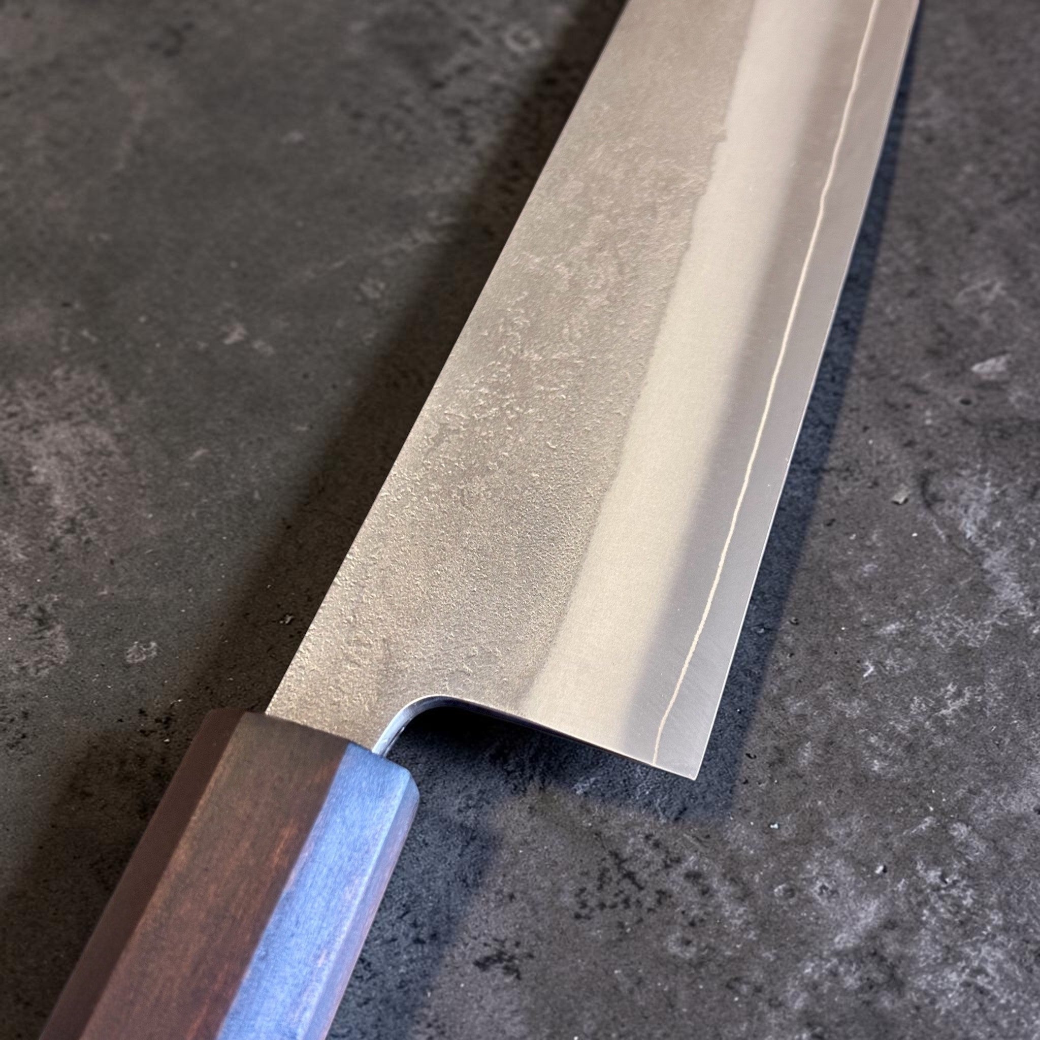 Yoshikane SKD Nashiji Gyuto 210 mm with mono ebony handle, close-up of nashiji blade finish and polished bevel.