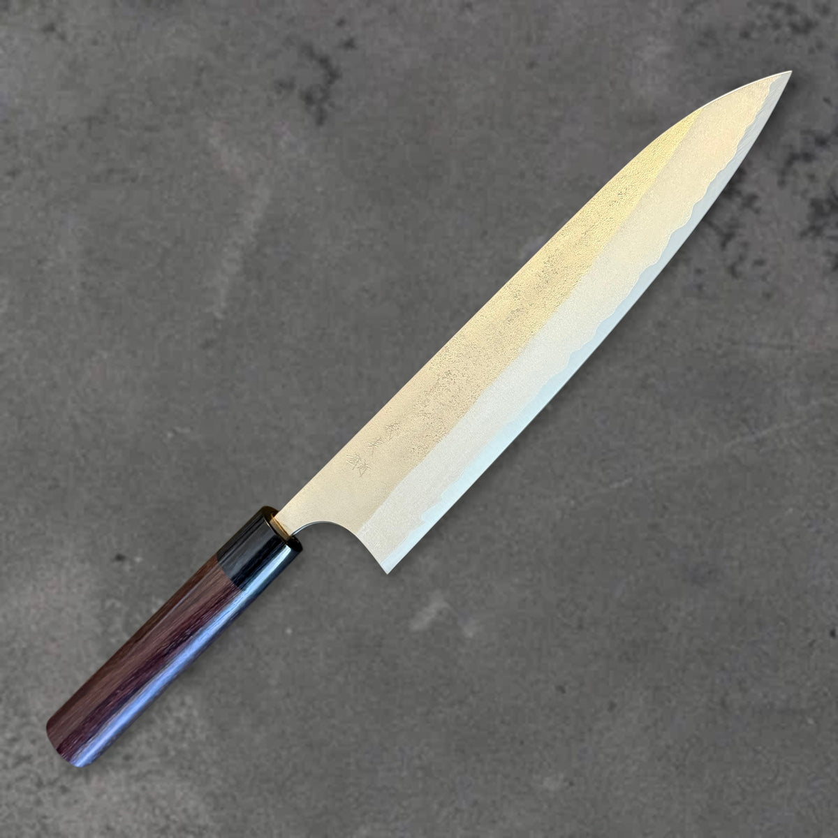 Angled front view of the Yoshimi Kato Aogami Super Nashiji 240mm gyuto showing its blade profile and dark wood handle.