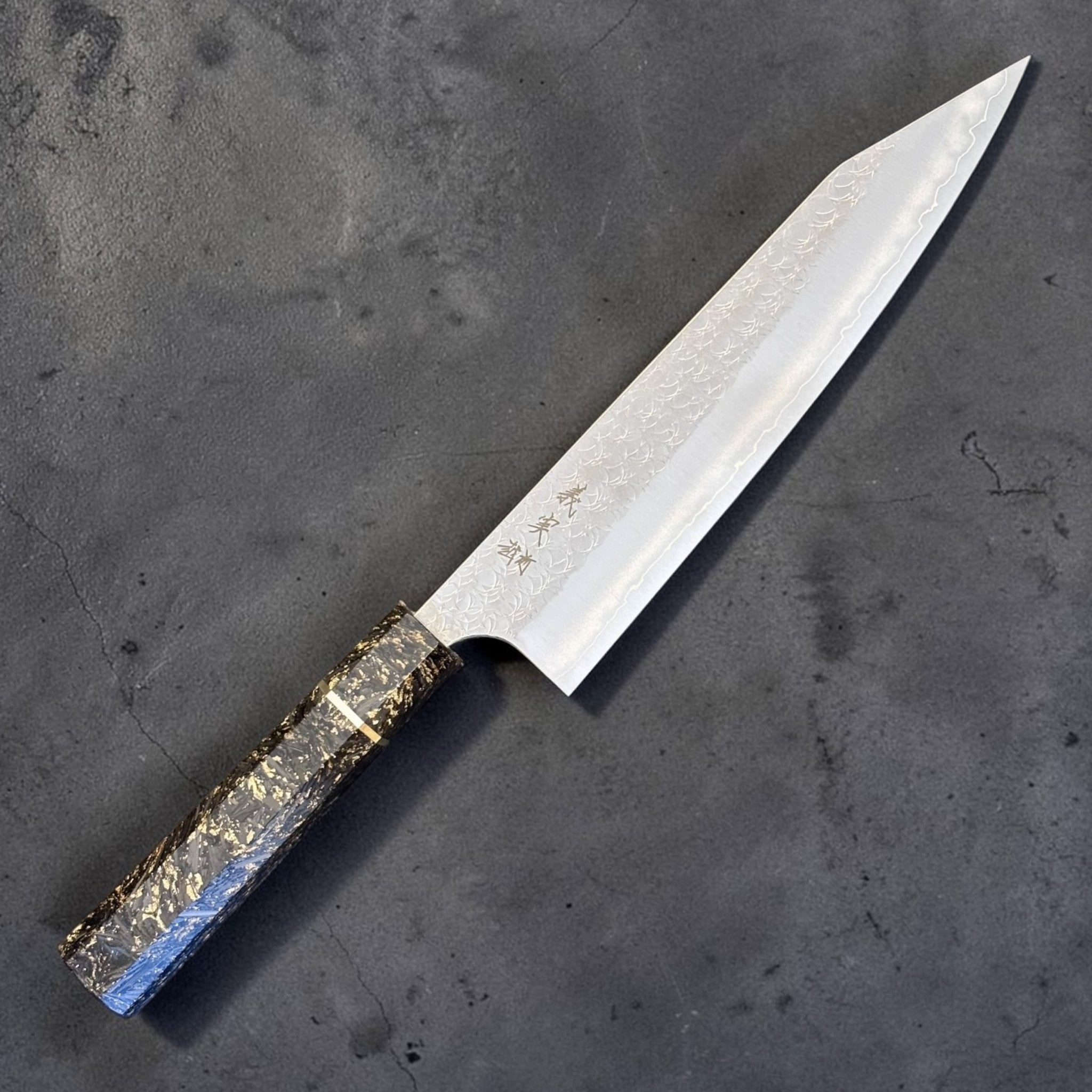 Yoshimi Kato Minamo SG2 Kiritsuke 210 mm with carbon fiber handle, angled full knife view showing patterned blade.