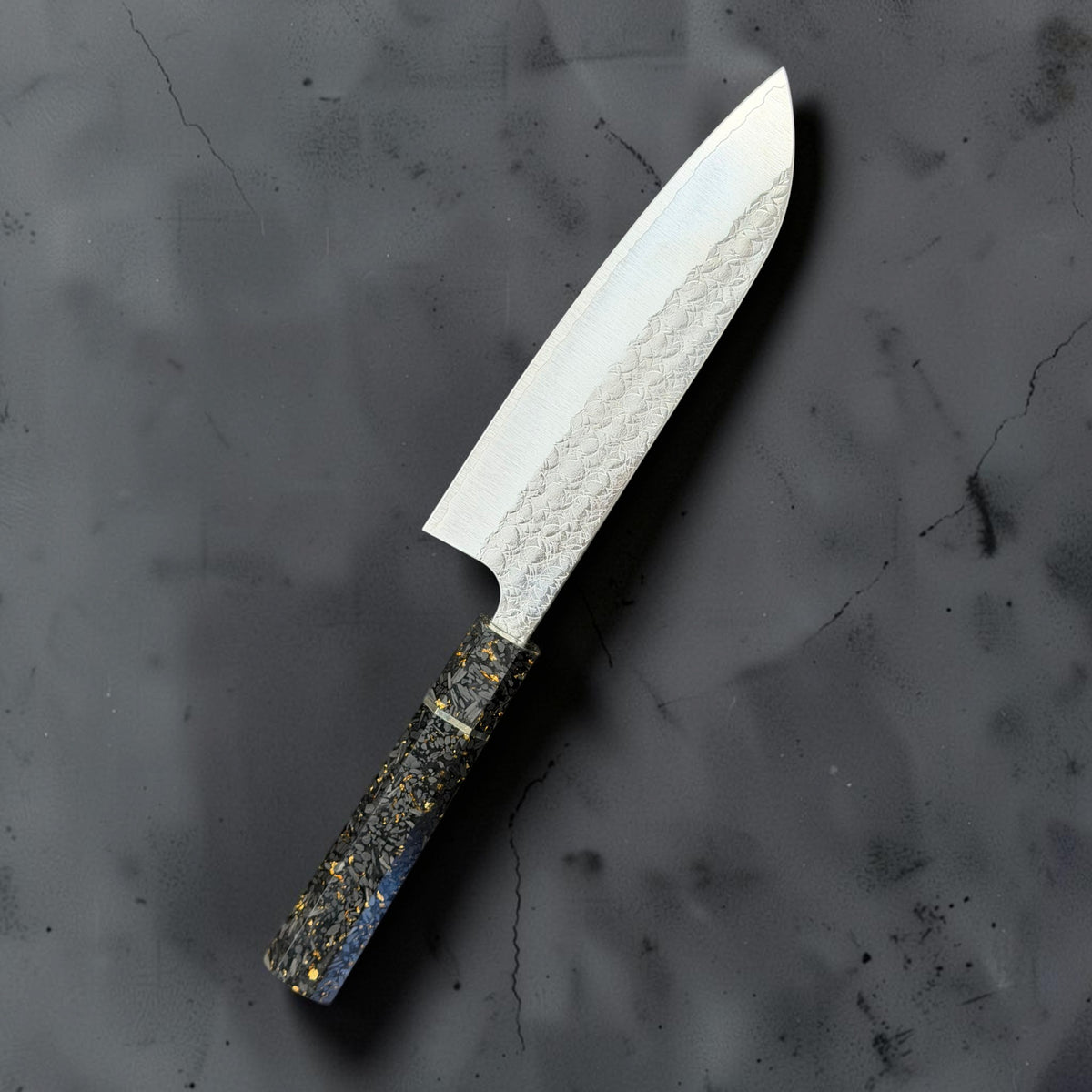Reverse angled view of the Yoshimi Kato Minamo SG2 santoku showing stainless cladding and the carbon fiber gold-fleck handle.