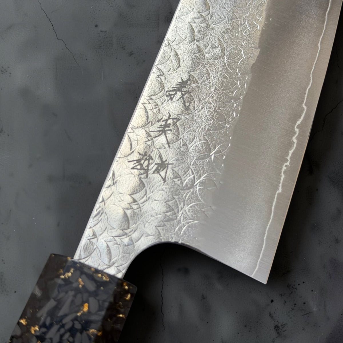 Close-up of Yoshimi Kato kanji, the Minamo hammered finish and the exposed SG2 cutting edge on the santoku.