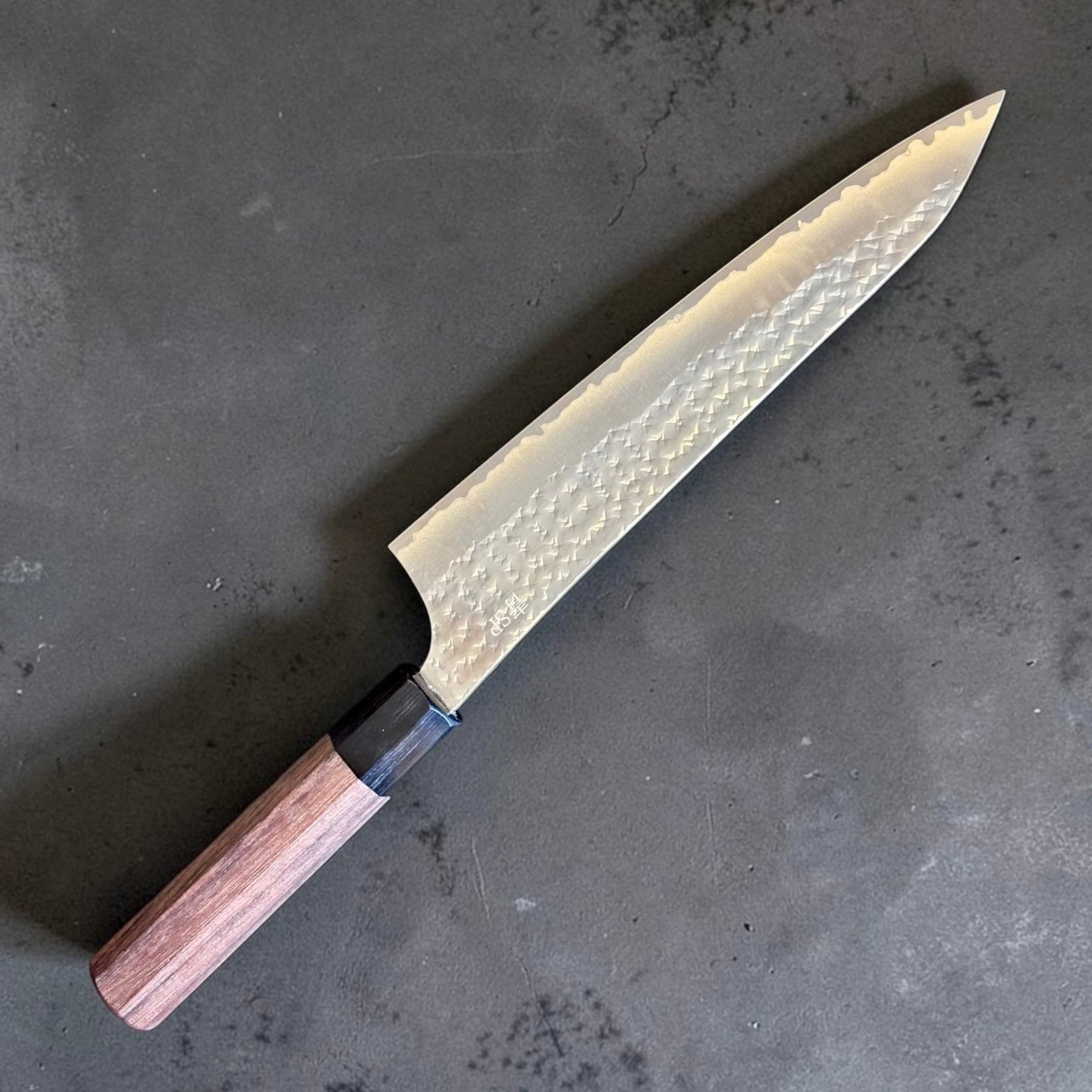 Yu Kurosaki Kokusen AS Gyuto 210mm with rosewood octagon wa handle on a dark stone background