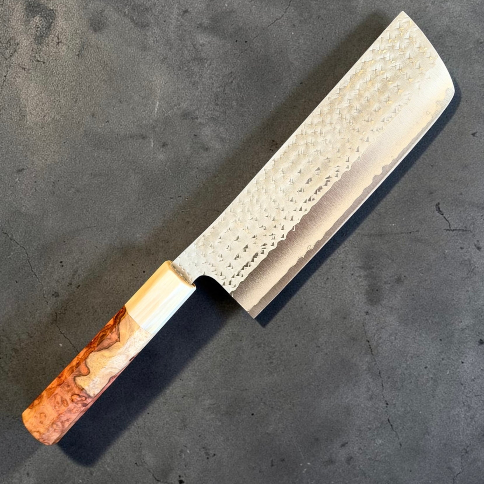 Angled view of the Yu Kurosaki Kokusen AS Nakiri 165mm showing its hammered blade and Amboyna burl handle