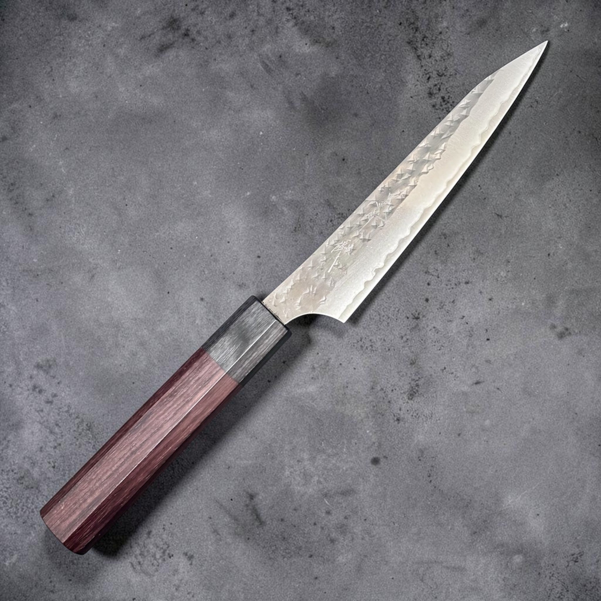 Yu Kurosaki Kokusen AS Petty 120 mm with rosewood octagon wa handle, angled full knife view showing the hammered blade finish.