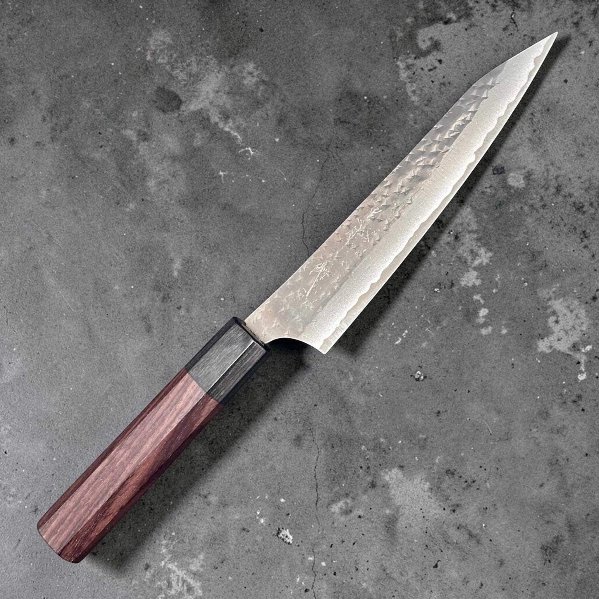 Yu Kurosaki Kokusen AS Petty 150 mm with rosewood octagon wa handle, angled full-profile view showing hammered blade texture and pointed petty tip.