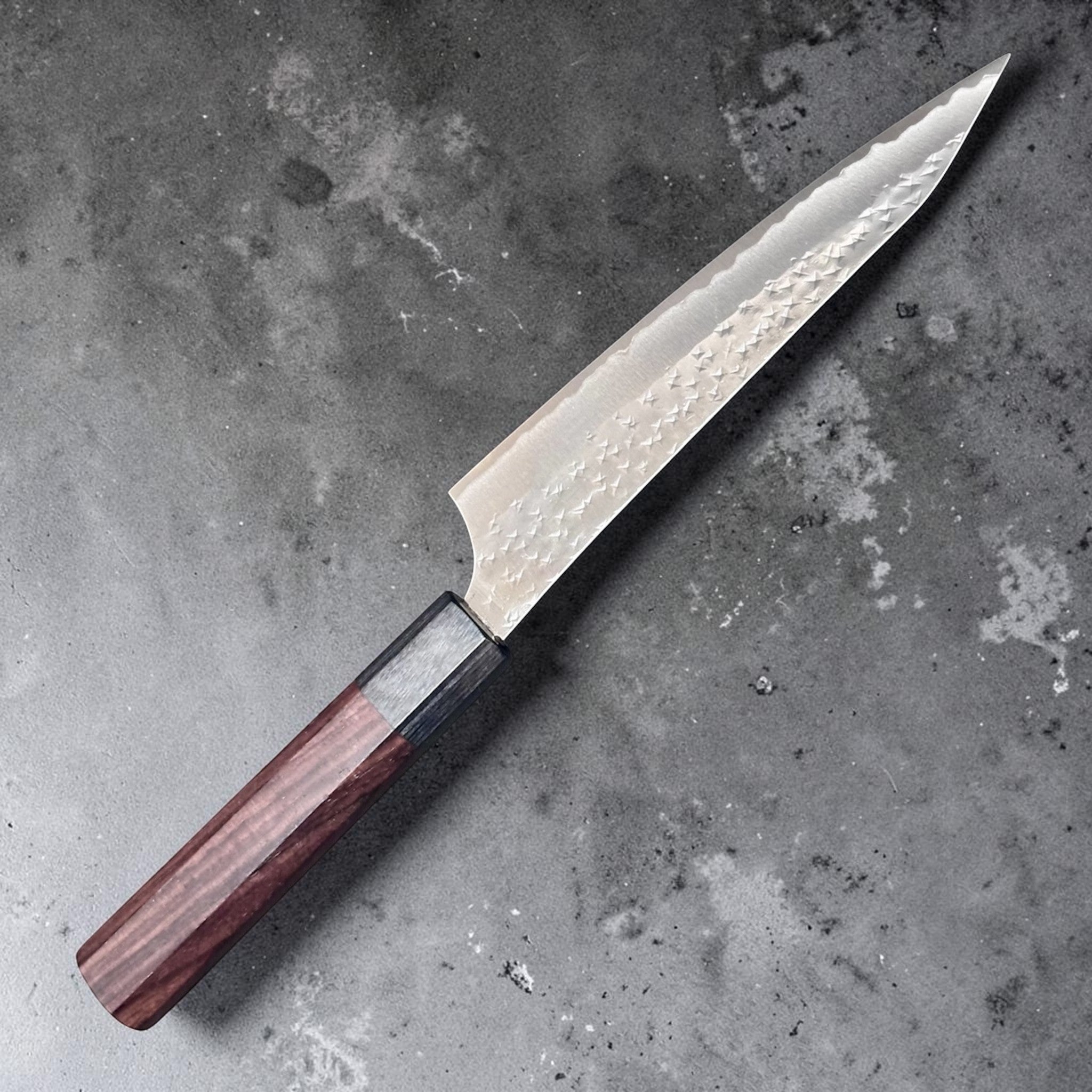 Yu Kurosaki Kokusen AS Petty 150 mm with rosewood octagon wa handle, close angled view highlighting the Kokusen hammered finish and black ferrule.