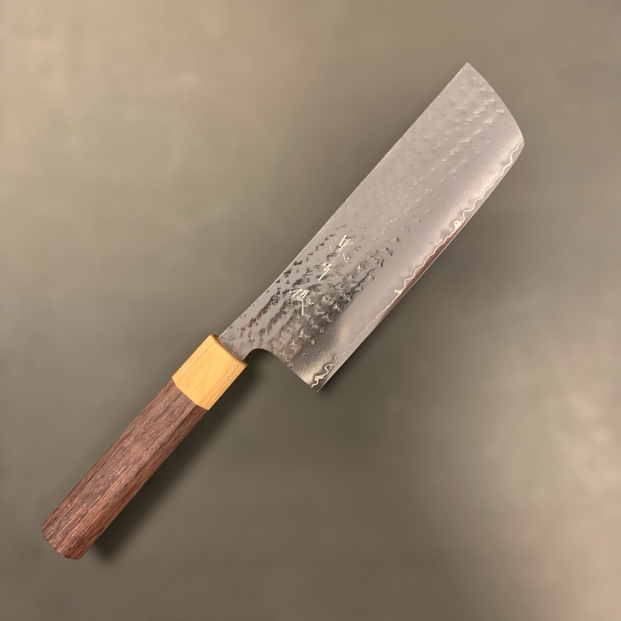 Yu Kurosaki Senko SG2 Ei Nakiri 165 mm, three-quarter blade view showing hammered tsuchime cladding, subtle hamon-like cladding line, and octagonal wa handle.