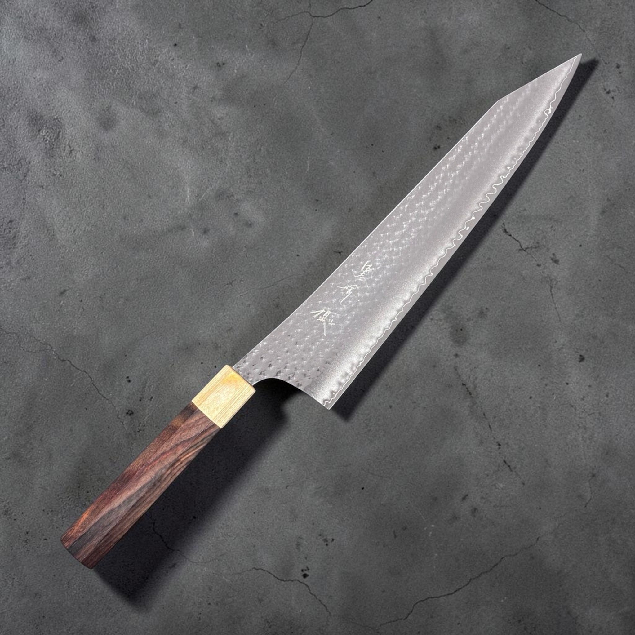 Yu Kurosaki Senko Ei SG2 Gyuto 270mm, angled view highlighting hammered pattern and tip.