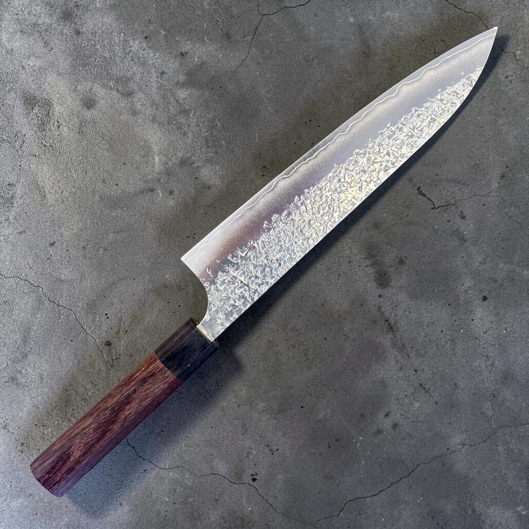 Yu Kurosaki Shizuku SG2 Gyuto 210 mm with rosewood octagonal handle, blade-side product photo highlighting hammered Shizuku texture and polished edge line.