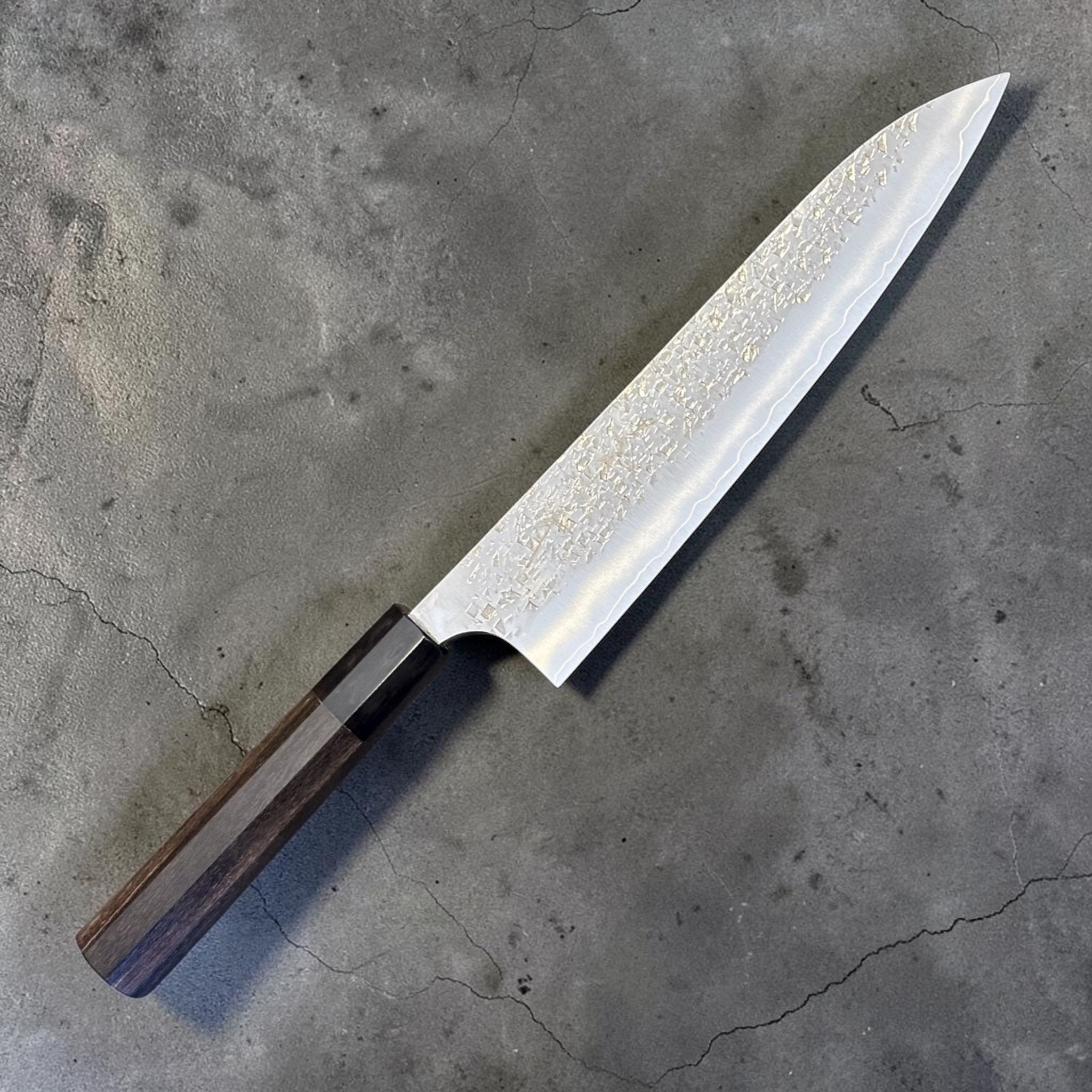 Yu Kurosaki Shizuku SG2 Gyuto 210 mm with ebony and black horn handle, angled full knife view showing hammered shizuku texture and polished blade.