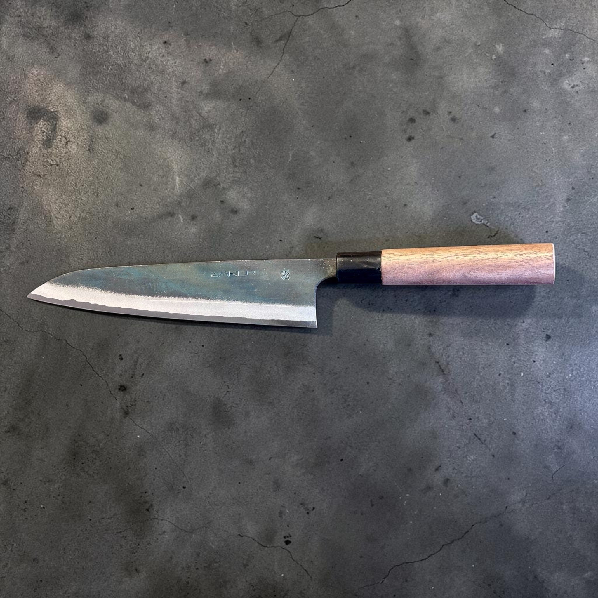 Zakuri AS Kurouchi Gyuto 210 mm, reverse-side horizontal profile showing the kurouchi blade and light wood wa handle.