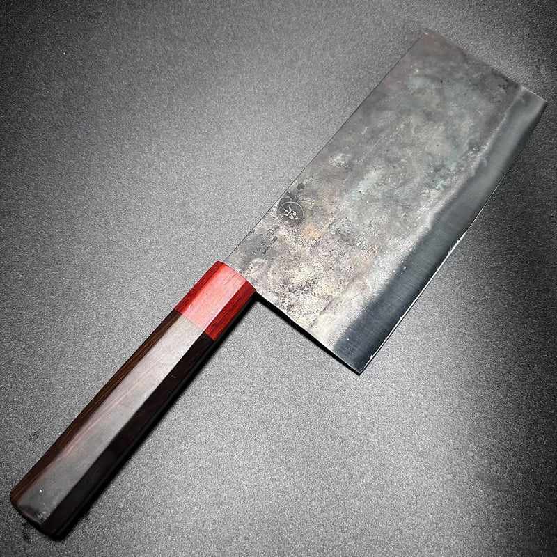 The DAO VUA V3 52100 Chinese Cleaver with its distinctive red handle, resting on a dark countertop