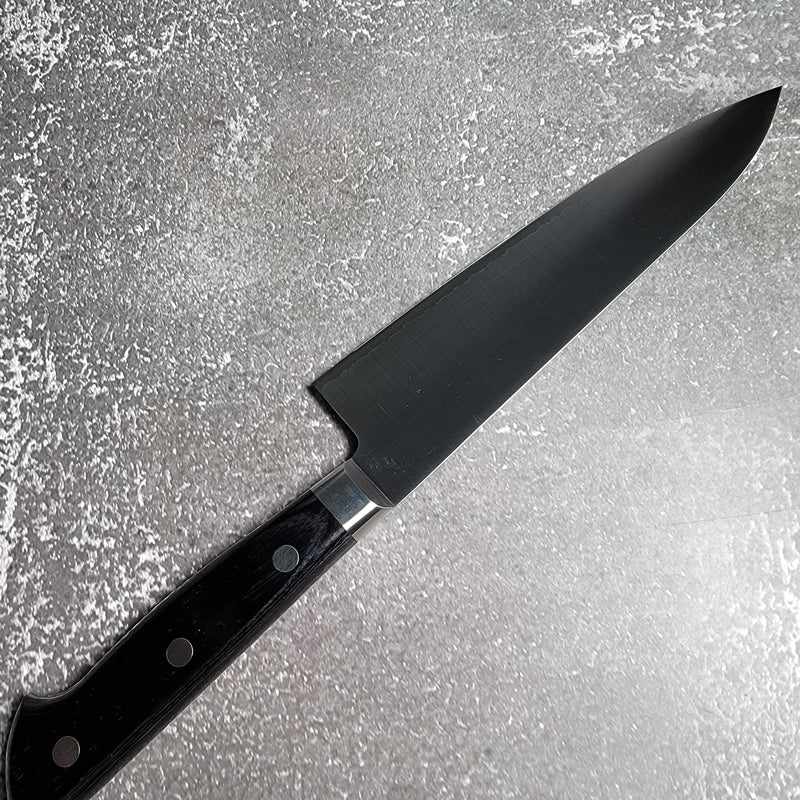 Takamura VG-10 Migaki Gyuto 180mm knife resting on a surface with a black western-style handle